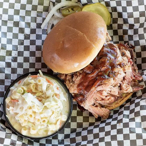 A sandwich and side dish on checkered paper.