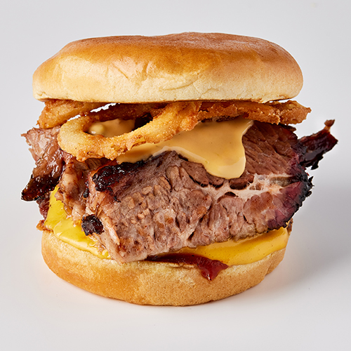 A hamburger with bacon, cheese and mustard on it.